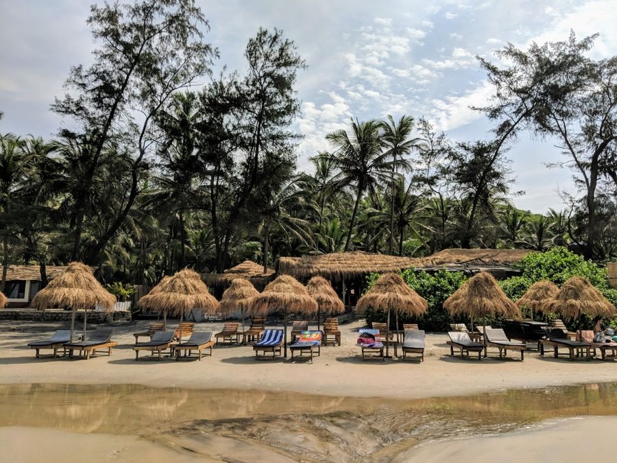 Beach loungers and thatched shade on a Goa shoreline