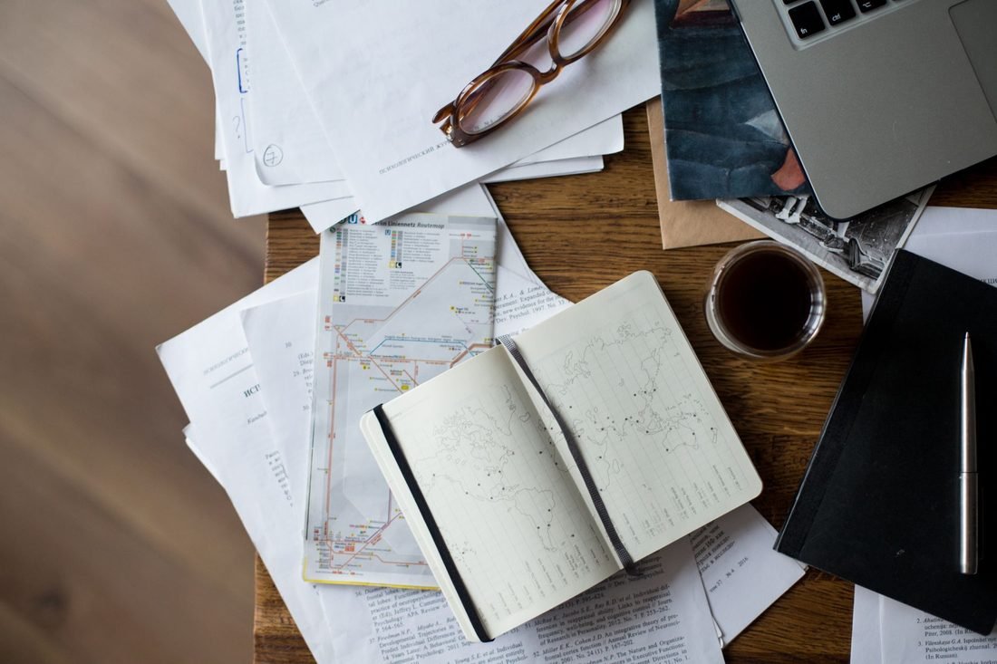 Travel planning desk with maps, documents and a laptop