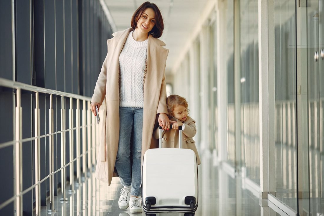 A parent and child walking through an airport gangway with luggage