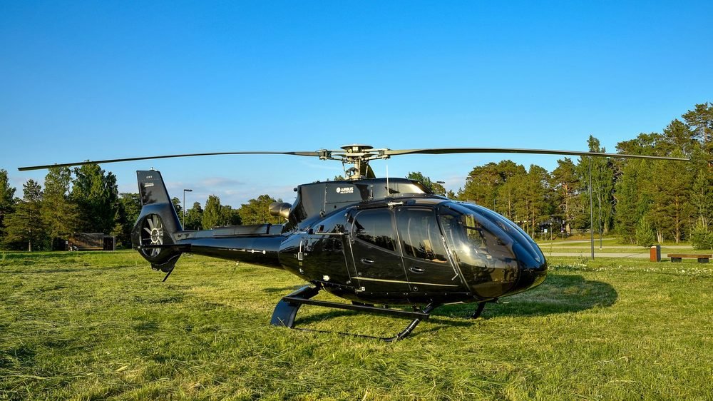 Light twin helicopter on a grass helipad ready for charter