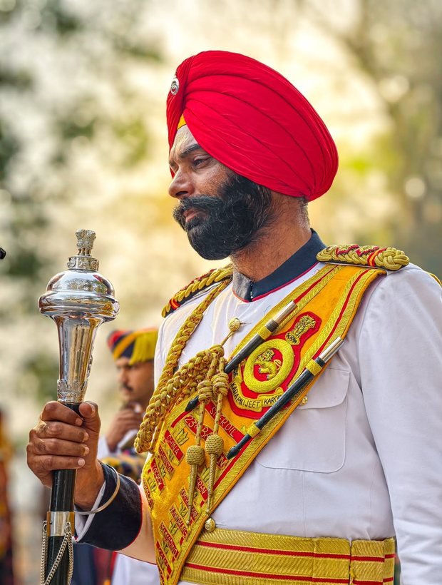 Ceremonial welcome attendant in white and gold uniform carrying a silver mace
